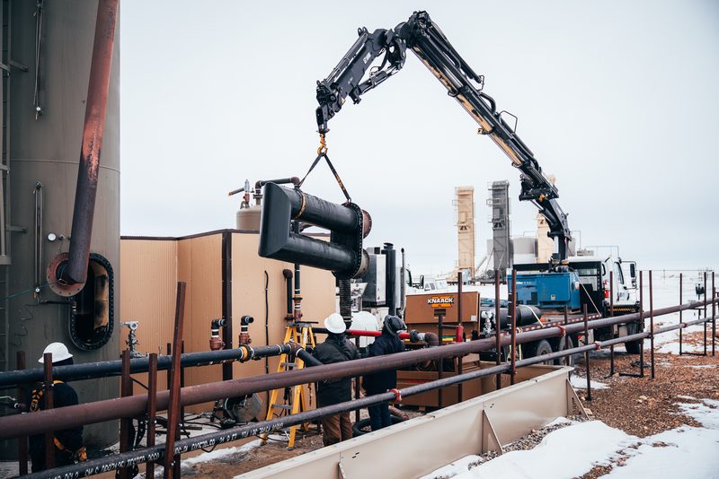 Elite crane truck lifting a spent twin-barrel fire tube clear of a heater treater