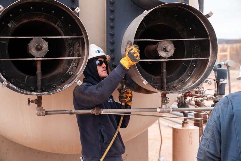 Field technician working the fire tube openings on a heater treater